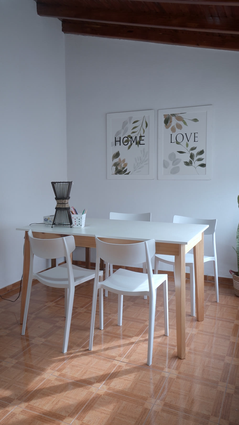 Consultorio con mesa de madera, sillas blancas, luz natural y cuadros